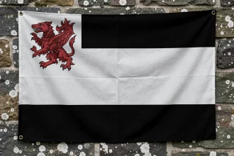 Drapeau breton Gwenn ha Du accroché sur un mur en pierre avec les bandes noires et blanches et les hermines visibles